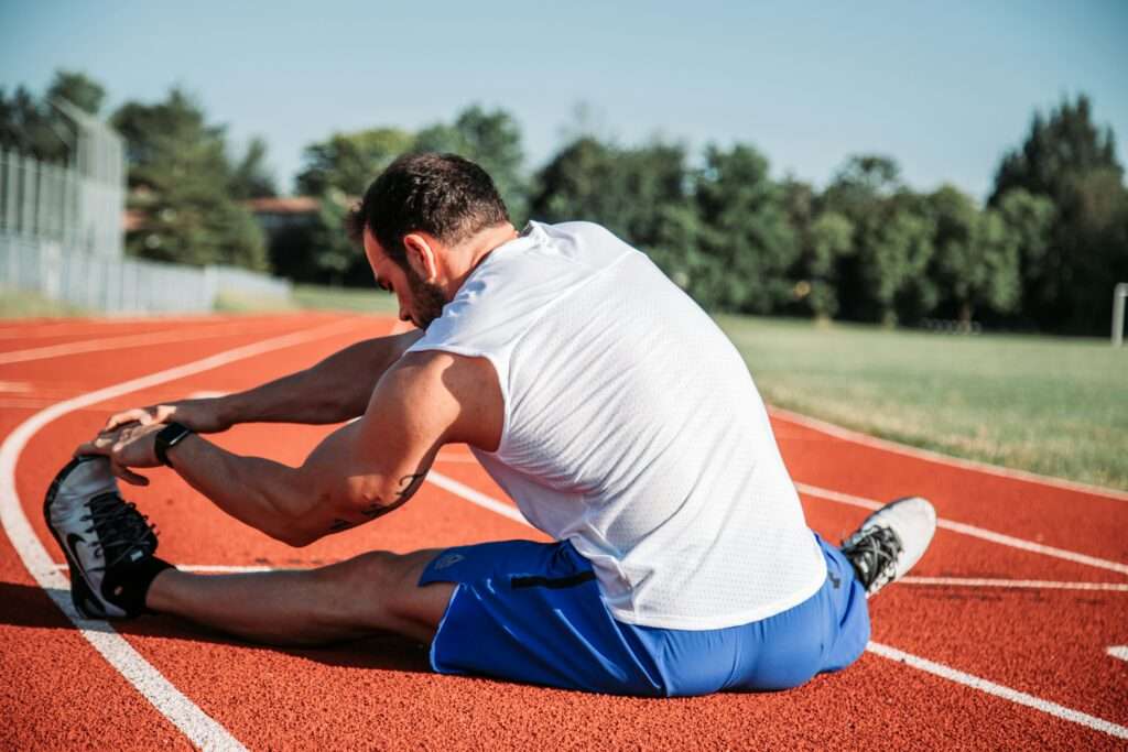 Man stretching his hamstrings on a track, statically.